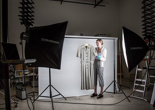 A person holds a grey dress in a photo studio