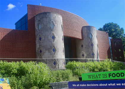 Front entrance of the Anacostia Community Museum with bushes in front and an exhibit sign partially reading What is food, and We all make decisions about what we eat