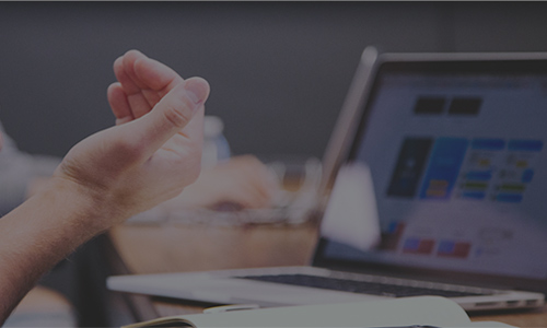 a person's right hand gestures in front of a laptop computer