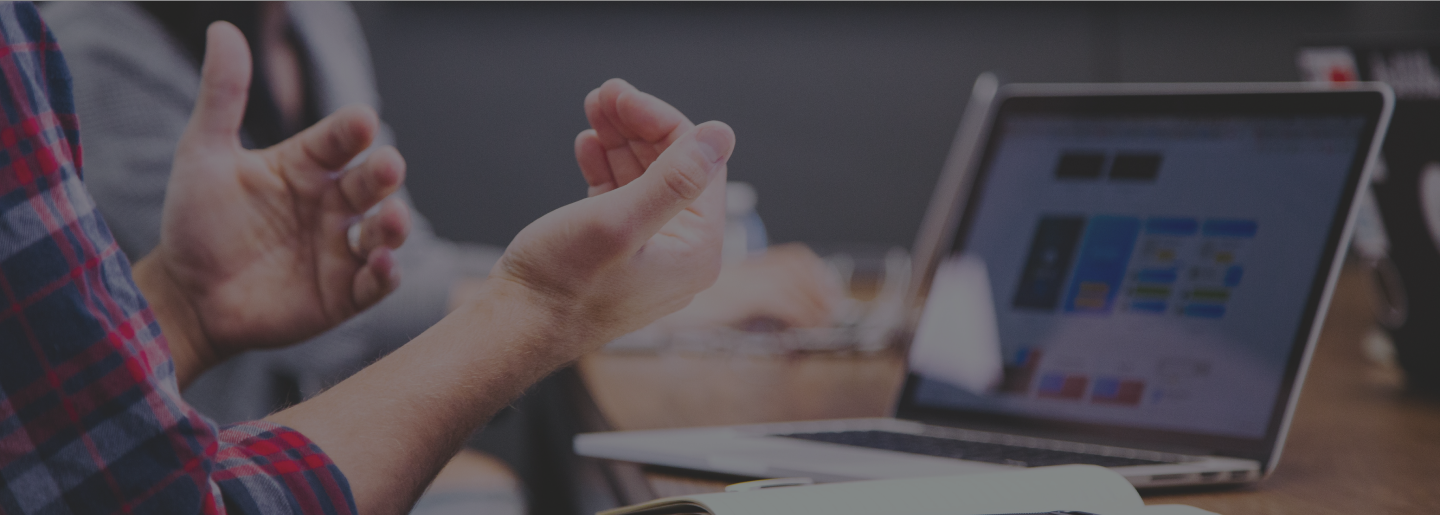 A set of hands gestures in front of a laptop sitting on a table