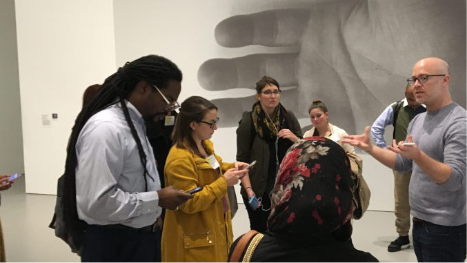 A group of people listen to a speaker in an art gallery.